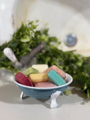 Vintage blue tub-style soap dish holding assorted mini bar soaps