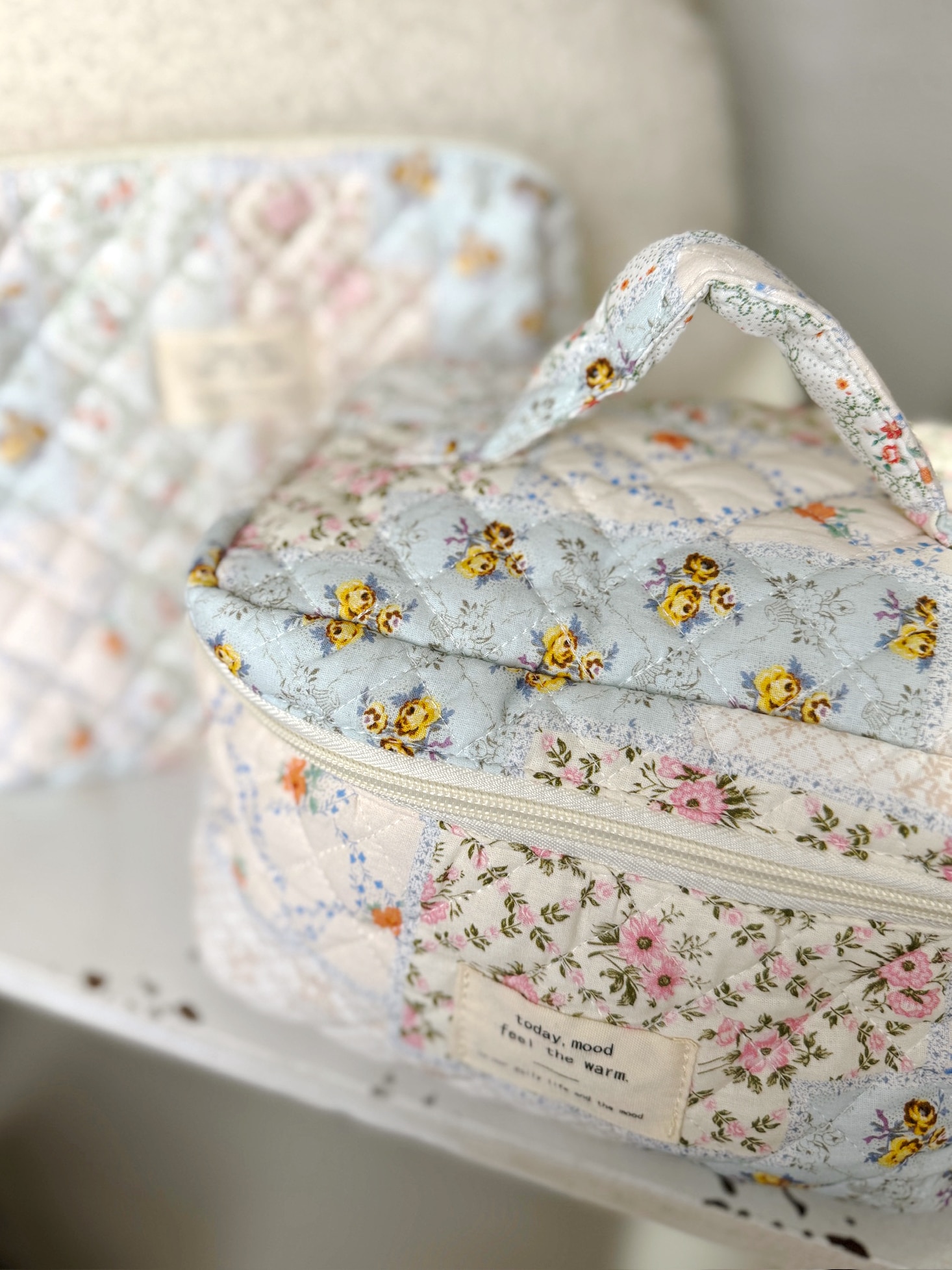 Vintage-inspired large floral quilted cosmetic bag with roomy interior, secure zip closure, and carry handle.