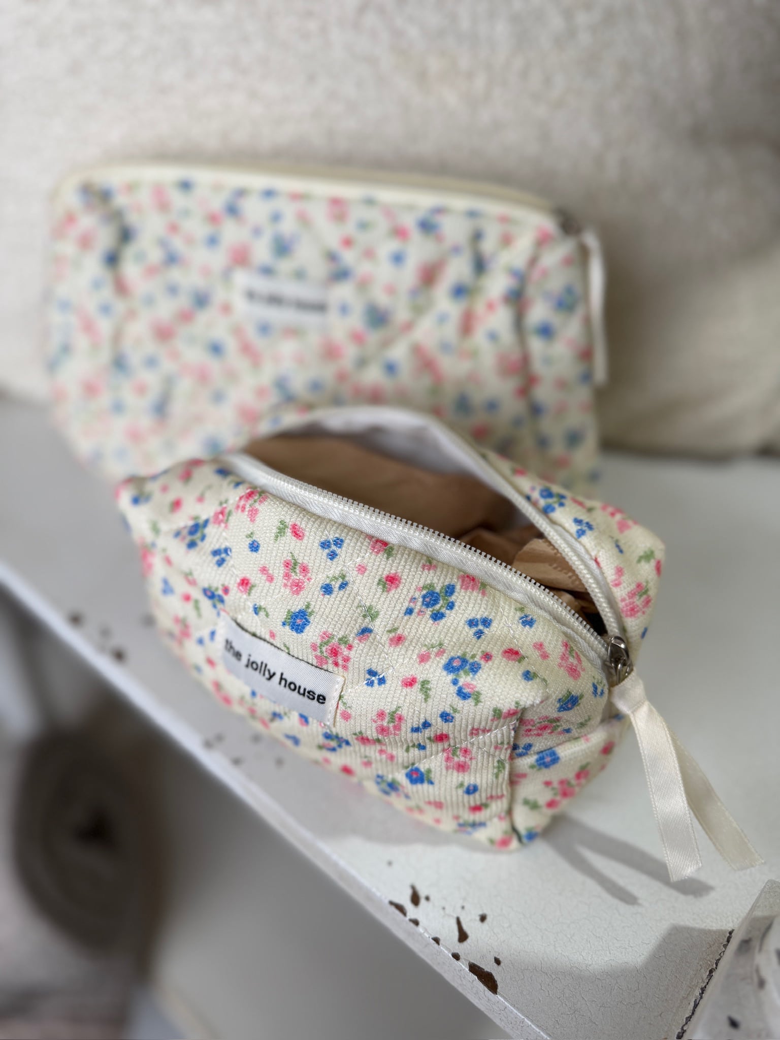 Small floral quilted corduroy travel pouch with zipper and ribbon pull tab detail.