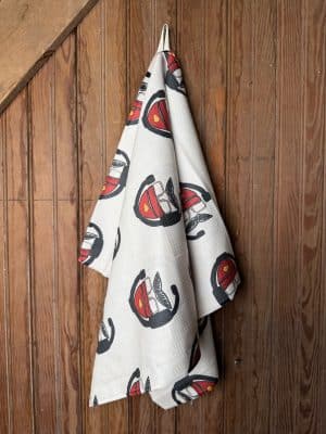 Microfiber KC Chiefs Big Red Tea Towel with a repeating red hat and mustache print, displayed flat and hanging on wood background.