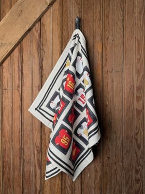 Double-sided Chiefs Jersey Hall of Fame Tea Towel featuring red and white jerseys bordered in black, displayed draped on wood paneling.