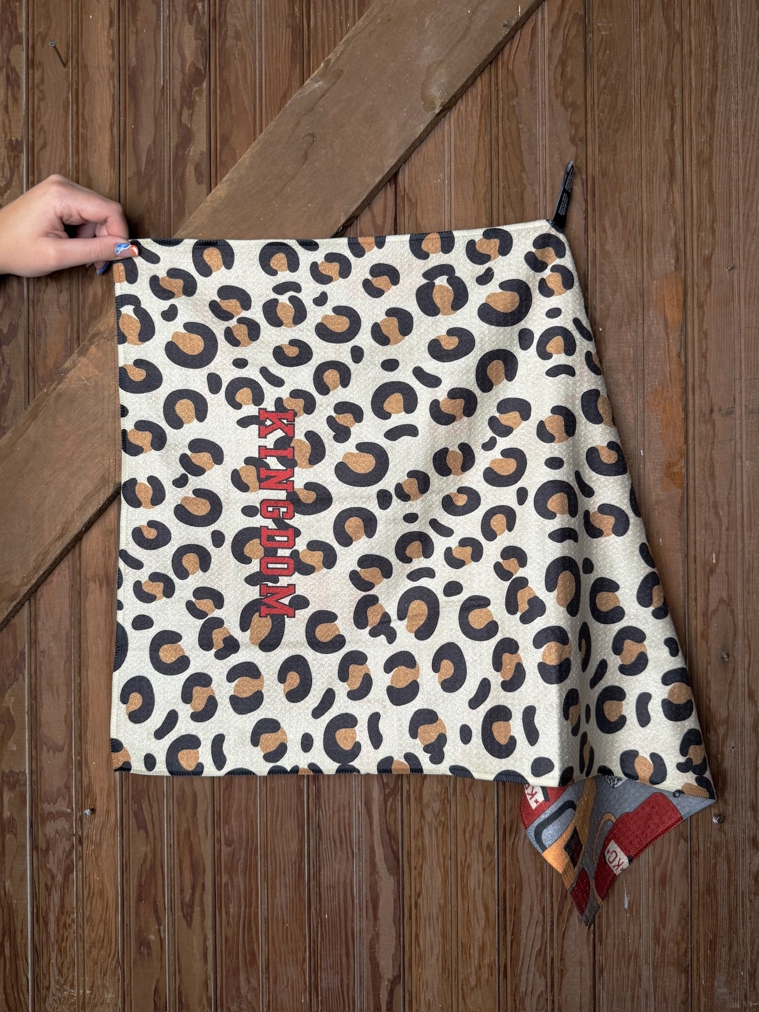 KC Chiefs Stanley & Leopard Print Tea Towel with leopard pattern on one side and tumbler graphics on the other, displayed hanging on wooden wall.