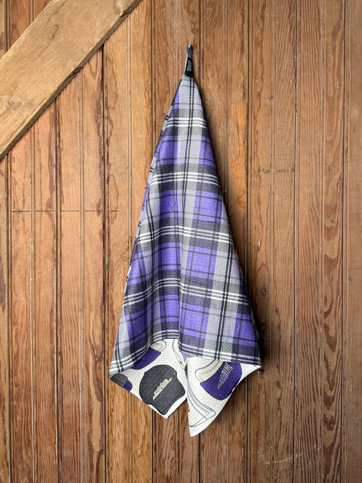 KSU Hats Tea Towel featuring purple, black, and gray hat designs with Wildcat and Manhattan details, shown hanging on a wooden wall.