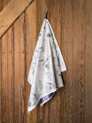 Wildcat Football Tea Towel with KSU-inspired vintage football illustrations and purple plaid back, hanging neatly on a wooden wall.