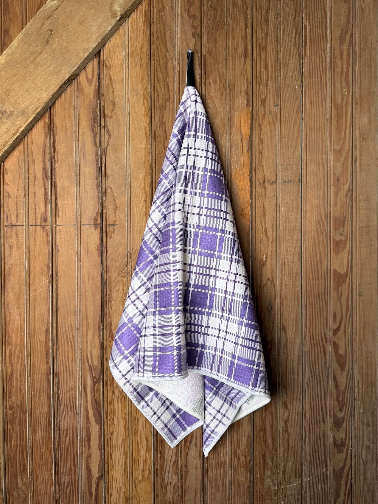 KSU Football Tea Towel featuring vintage football artwork and K-State landmarks with a purple plaid reverse, displayed hanging on a wood background.
