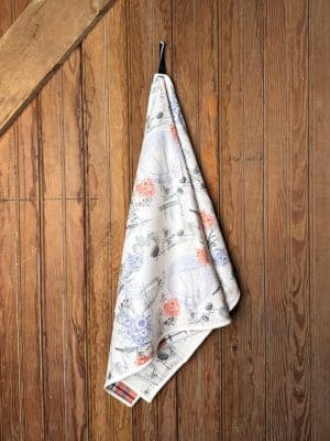 Full hanging view of KU 1912 Basketball Tea Towel featuring sketch-style artwork of KU landmarks, basketballs, and florals in red and blue tones.