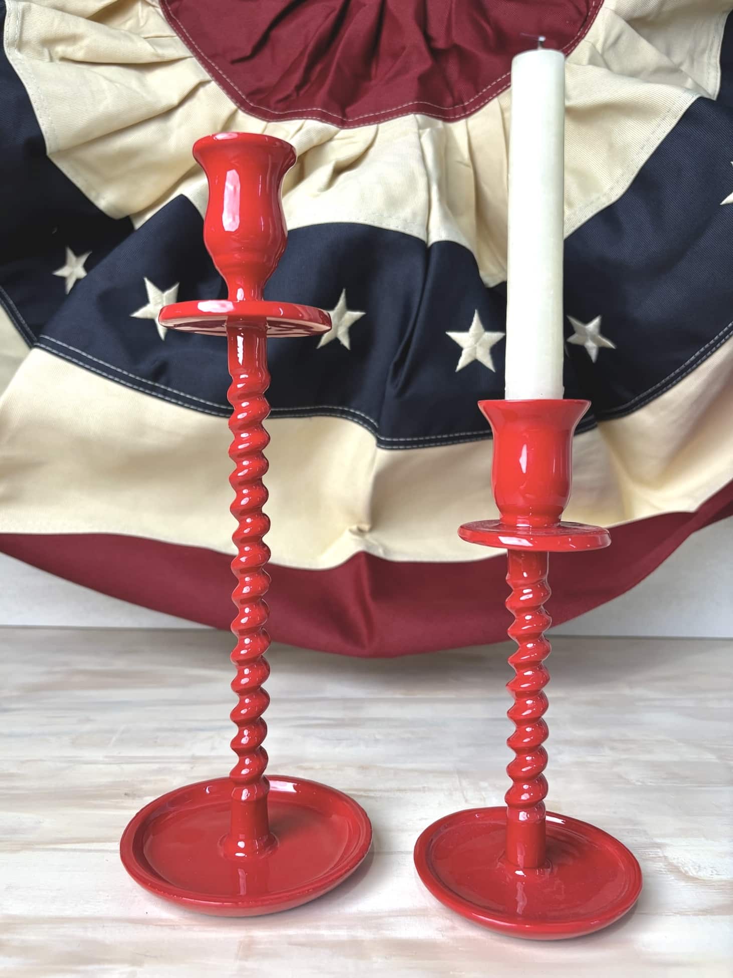 Red Corkscrew Taper Candle Holders in two sizes, styled with a white taper candle and patriotic bunting in the background.