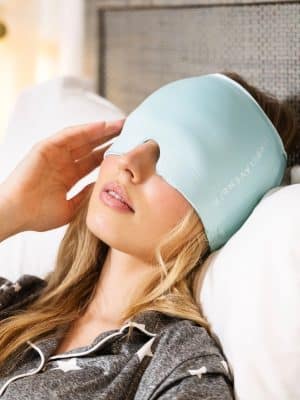 Woman wearing a blue Migraine Cap Temp Smart while relaxing on a bed.