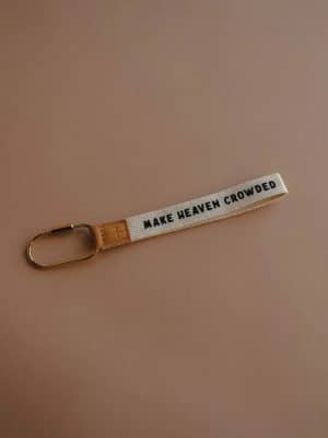 Fabric wristlet keychain reading “Make Heaven Crowded,” featuring a leather cross tag and sturdy gold carabiner.