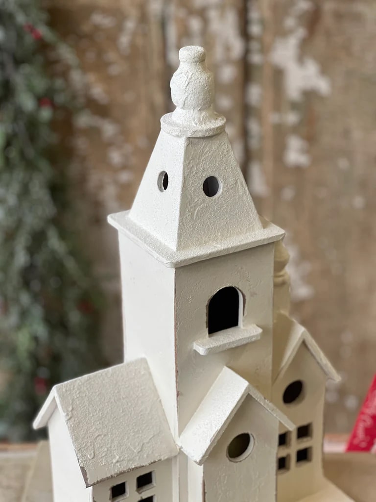 Side view of a distressed white chapel figurine with layered rooftops, arched windows, and a subtle glitter finish.