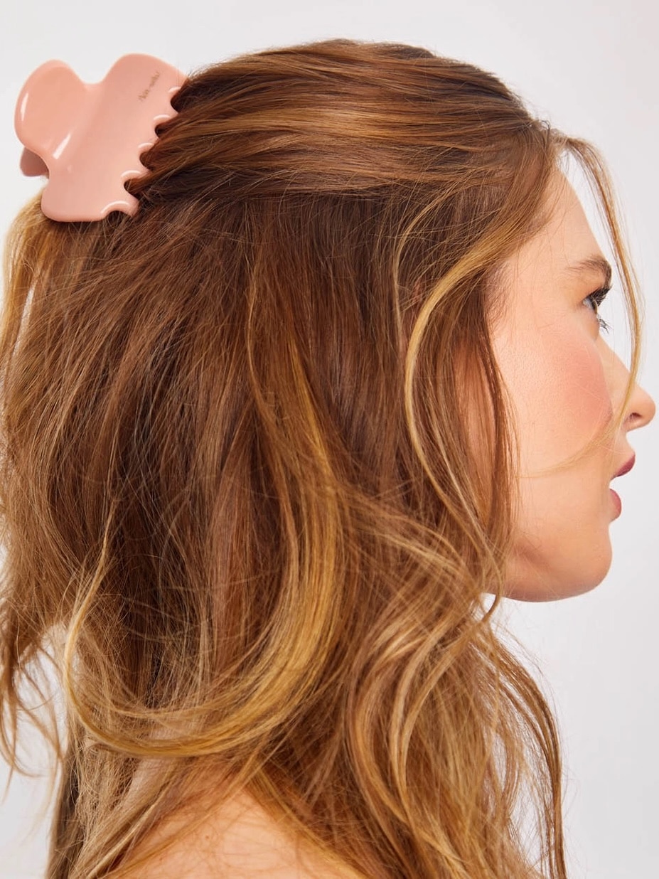 Woman with wavy hair wearing a rosewood puffy claw clip made from recycled plastic.