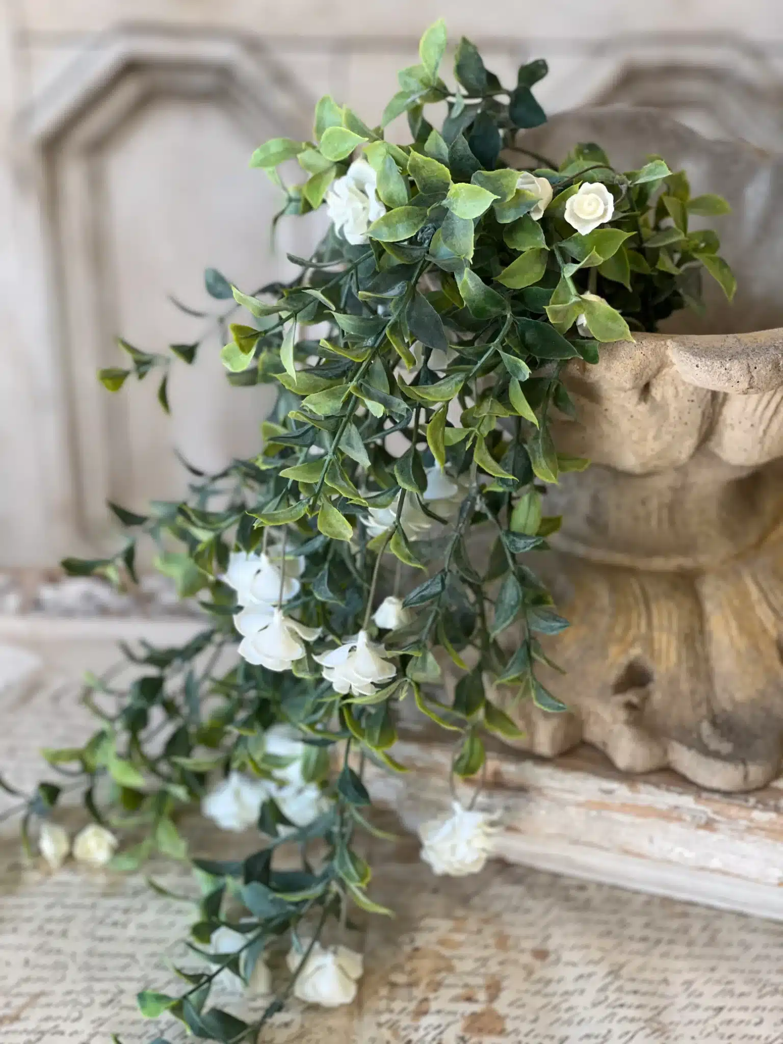 White Rosarium Florets Hanging Stem draped over a decorative pedestal with trailing greenery