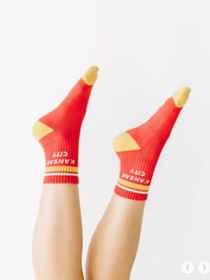 Unisex red and gold Kansas City crew socks styled with sneakers, fits women’s 6–9 and men’s 4.5–8.