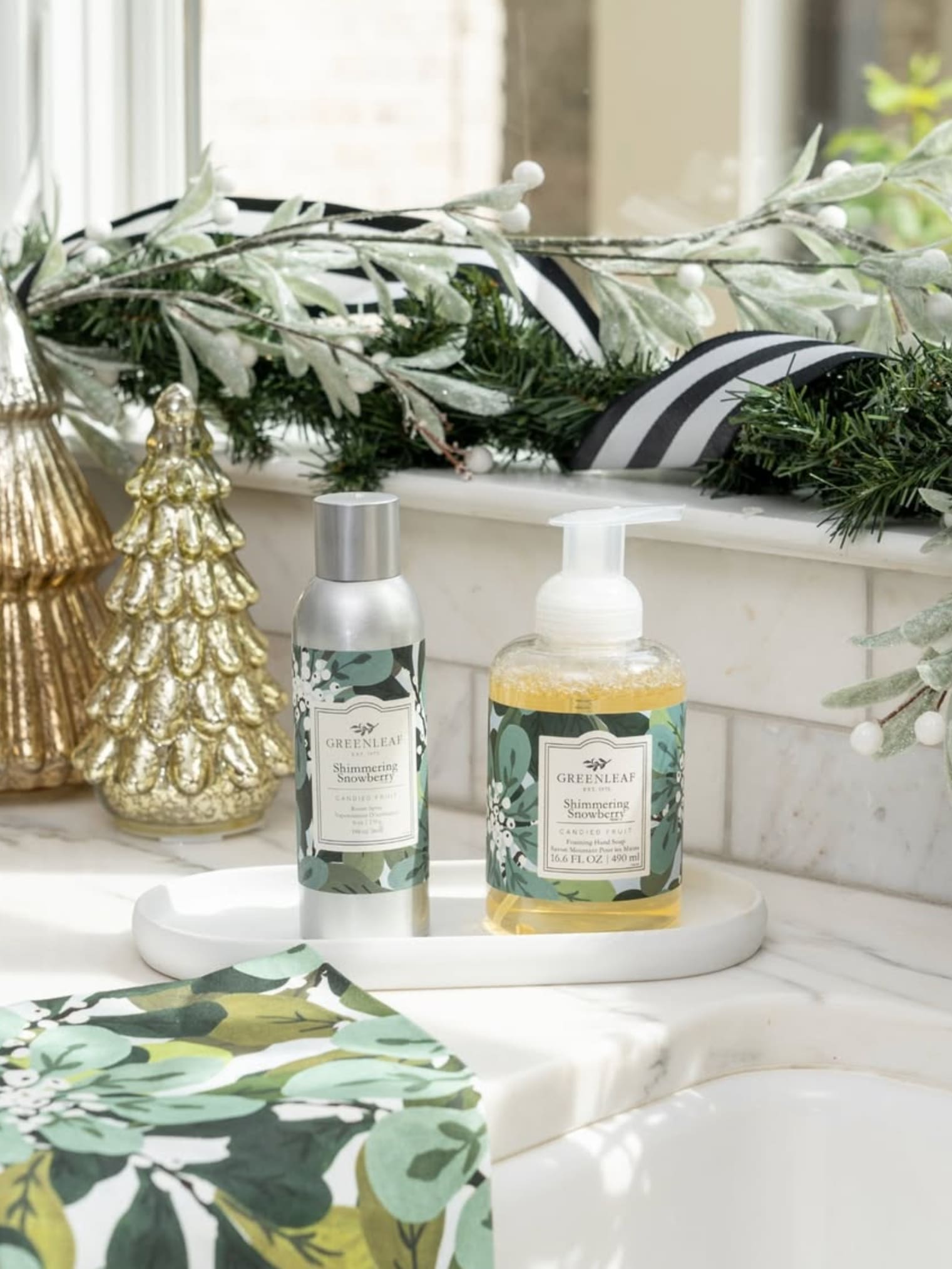 Greenleaf Shimmering Snowberry Foaming Hand Soap and Room Spray displayed with holiday décor on a kitchen counter.
