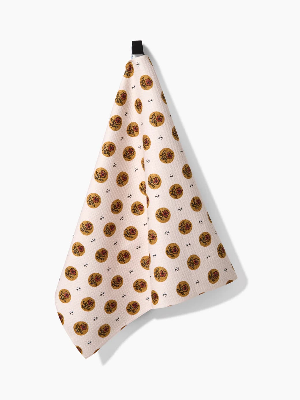 Artisanal Floral Cream Geometry Towel with repeating golden floral circle design on a cream background, hanging from a hook.