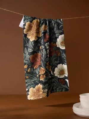 Classic Floral Geometry Towel with oversized rust, tan, and white flowers on a black background, hanging in a kitchen setting.