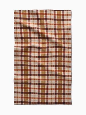 Flat-lay of Maple Jane Geometry Towel showing full cream microfiber fabric with plaid design in rust, orange, and brown hues.