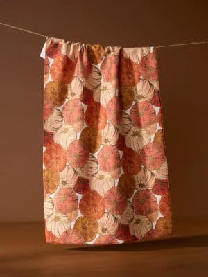 Tendril Geometry Towel with white background and medium-sized pumpkins in orange, rust, and off-white hues, hanging in a cozy fall kitchen.
