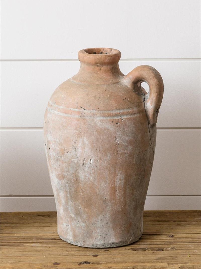 Tuscan-style terracotta vase with a weathered, aged finish and single side handle, set on a rustic wooden surface.
