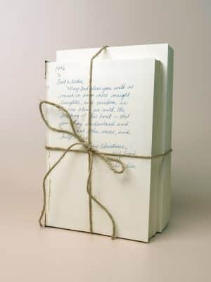 Cream and white softcover vintage books stacked and tied with twine, handwritten text visible