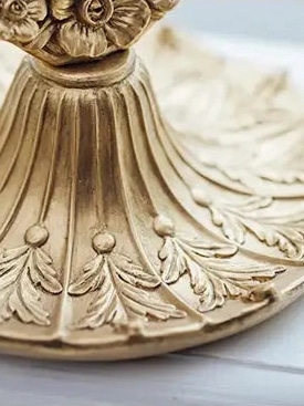 Close-up detail of the gold ornate vintage vanity mirror base with carved design.