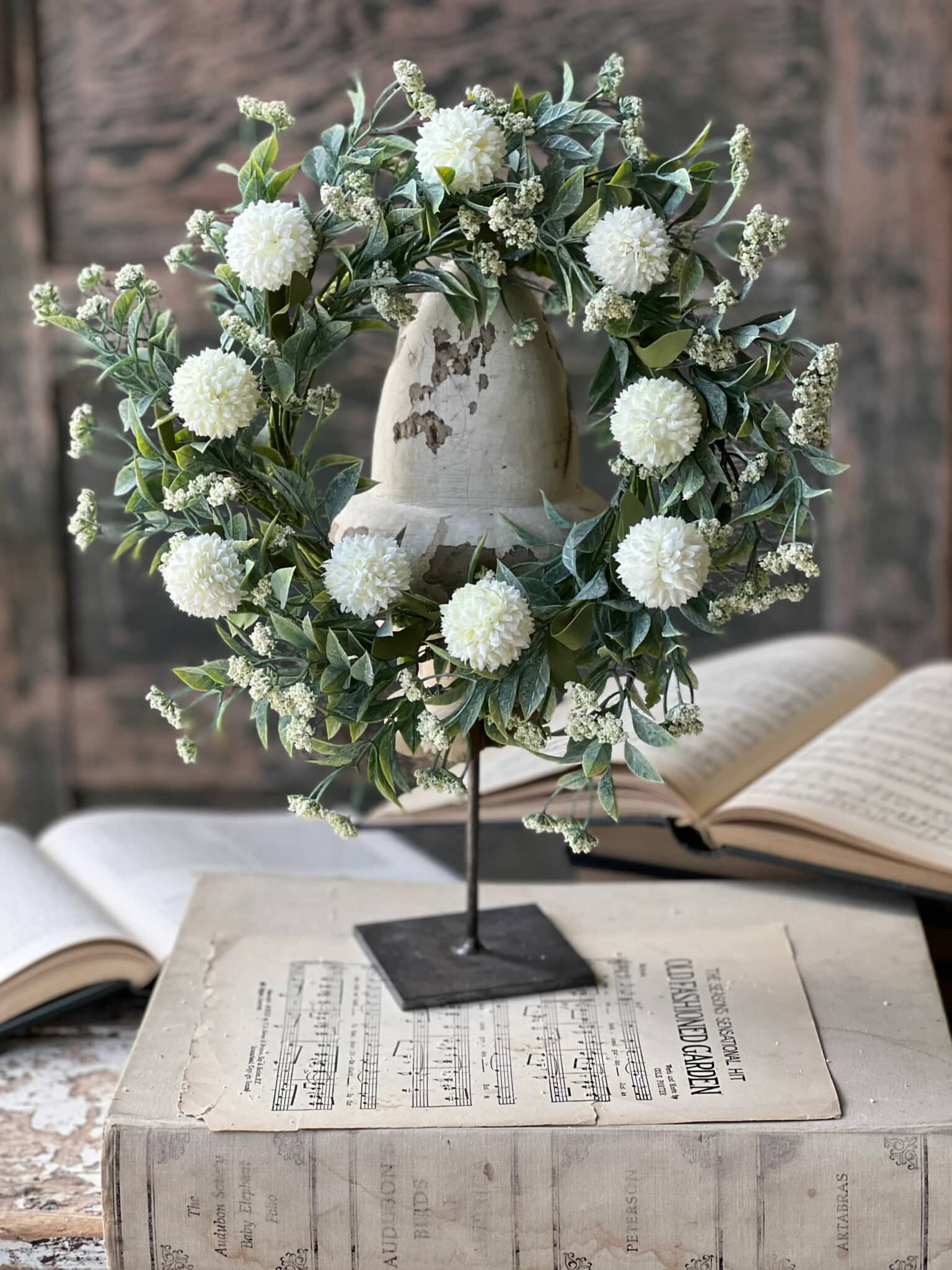 White Garden Pom Candle Ring with soft white pom blooms and mixed greenery displayed on a metal stand