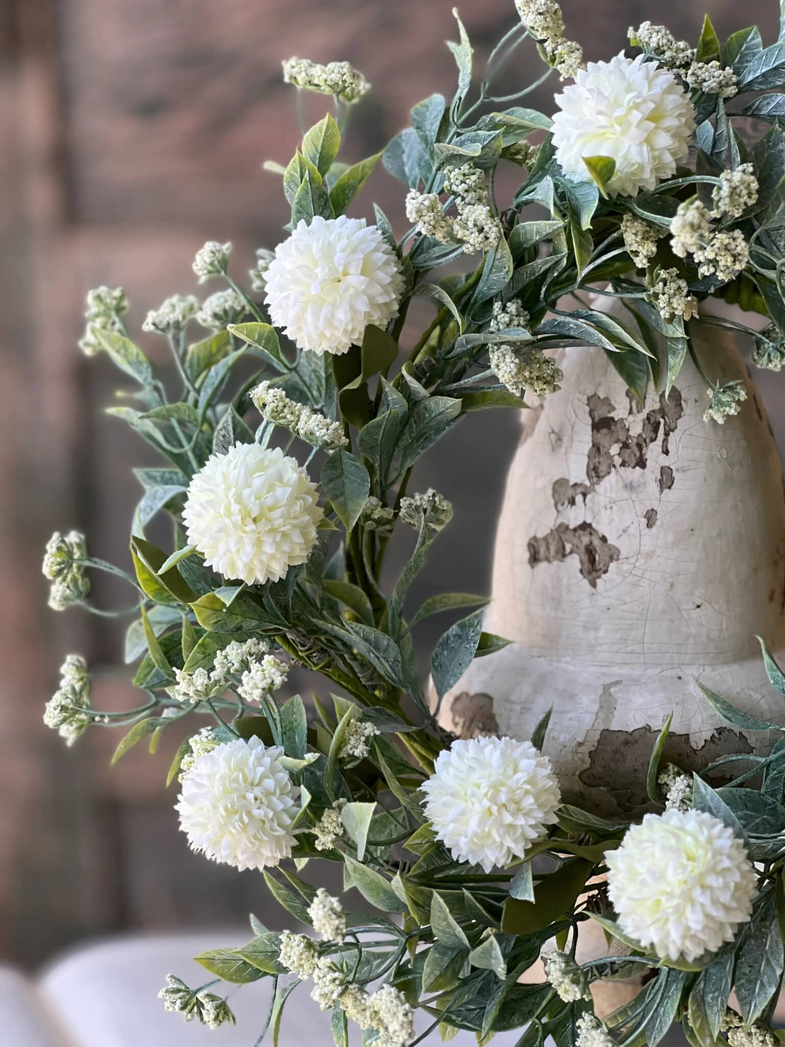 Close-up of White Garden Pom Candle Ring featuring textured white pom flowers and layered greenery