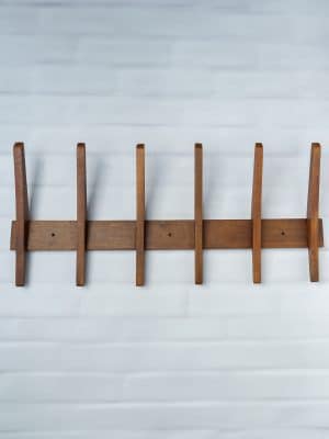 Large wooden wall rack with five curved pegs mounted against a white wall, showcasing a warm wood finish and modern minimalist design.