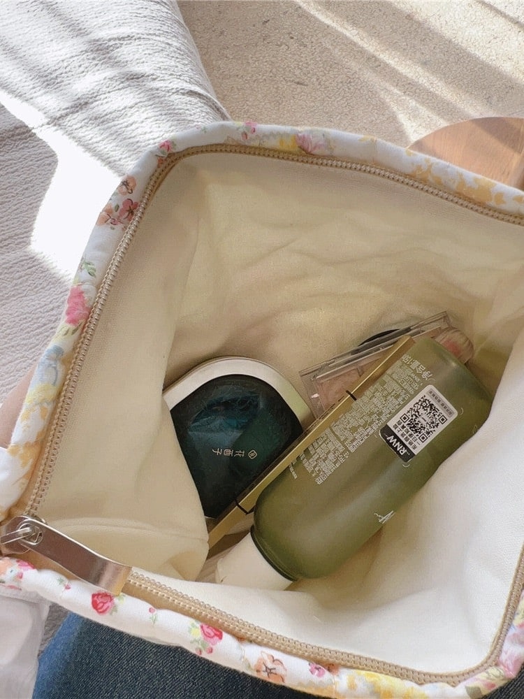 Inside view of a quilted makeup bag showing beige cotton canvas lining and beauty items