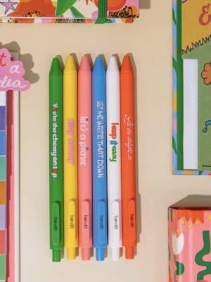 Six colorful Ban.do gel pens with playful sayings like “Stay Sunny” and “Let Me Write That Down.”