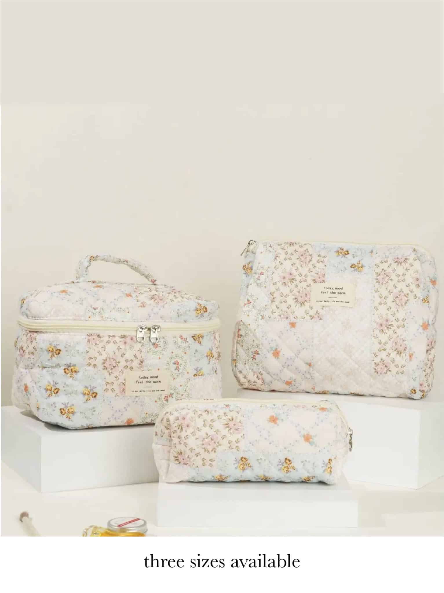 Set of three quilted floral makeup bags in small, medium, and large sizes with coordinating pastel patchwork design.