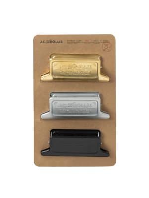 Front view of a set of three binder clips in brass, silver, and black displayed on kraft paper packaging