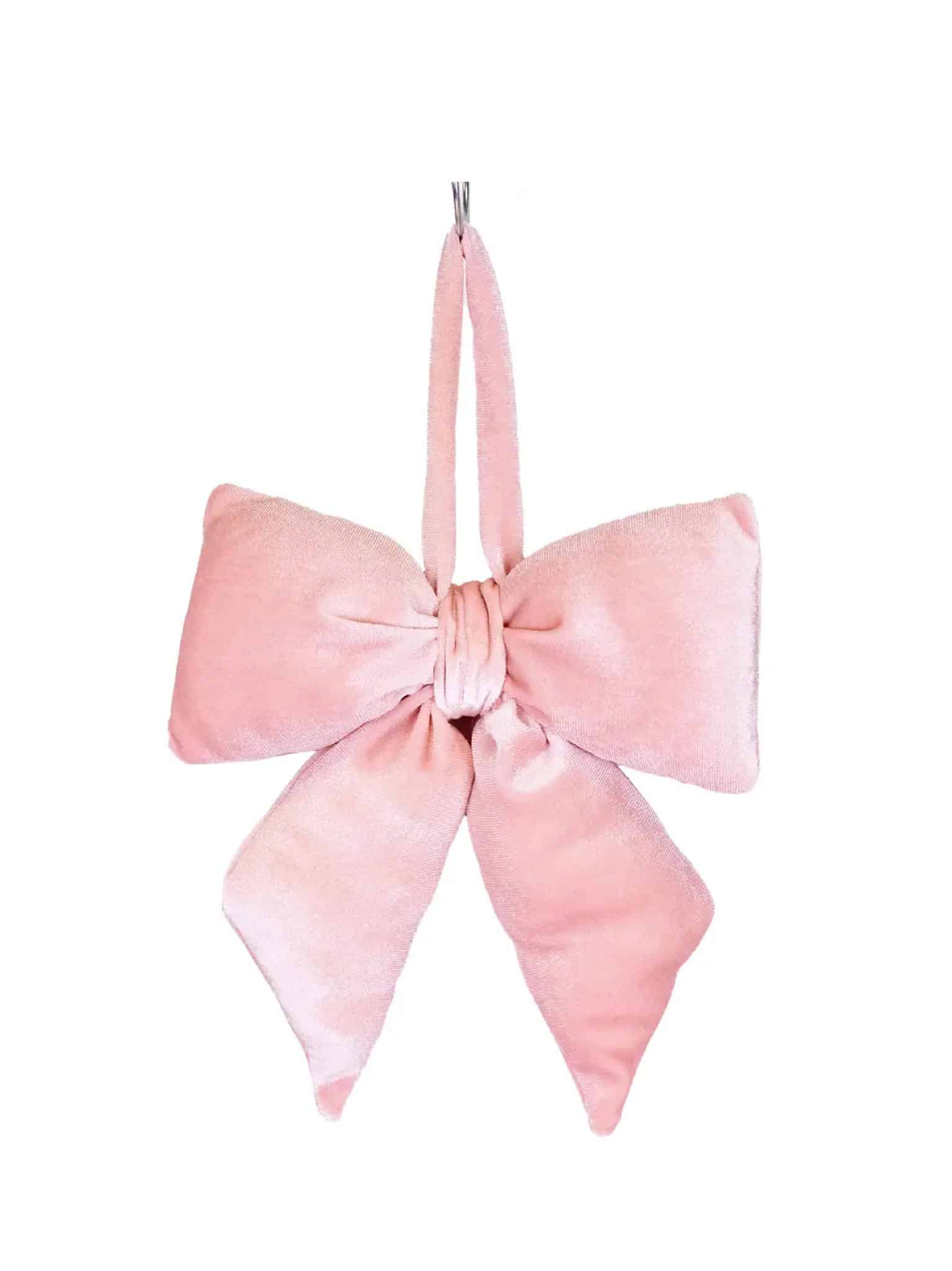 Light pink velvet bow ornament with long tails and a hanging loop, displayed against a white background.
