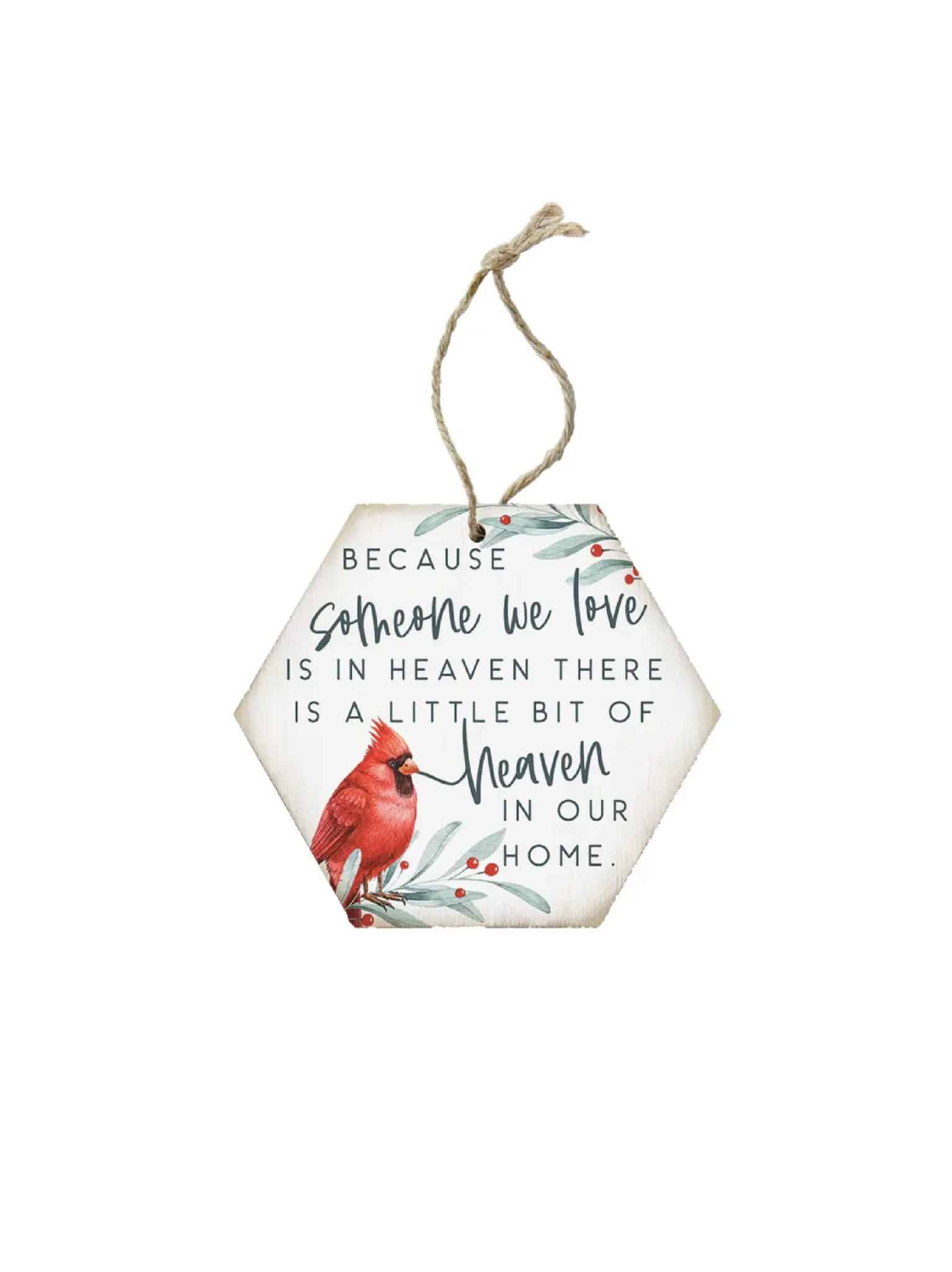 Hexagon wooden ornament with a red cardinal and the phrase “Because someone we love is in heaven, there is a little bit of heaven in our home,” hanging by twine.