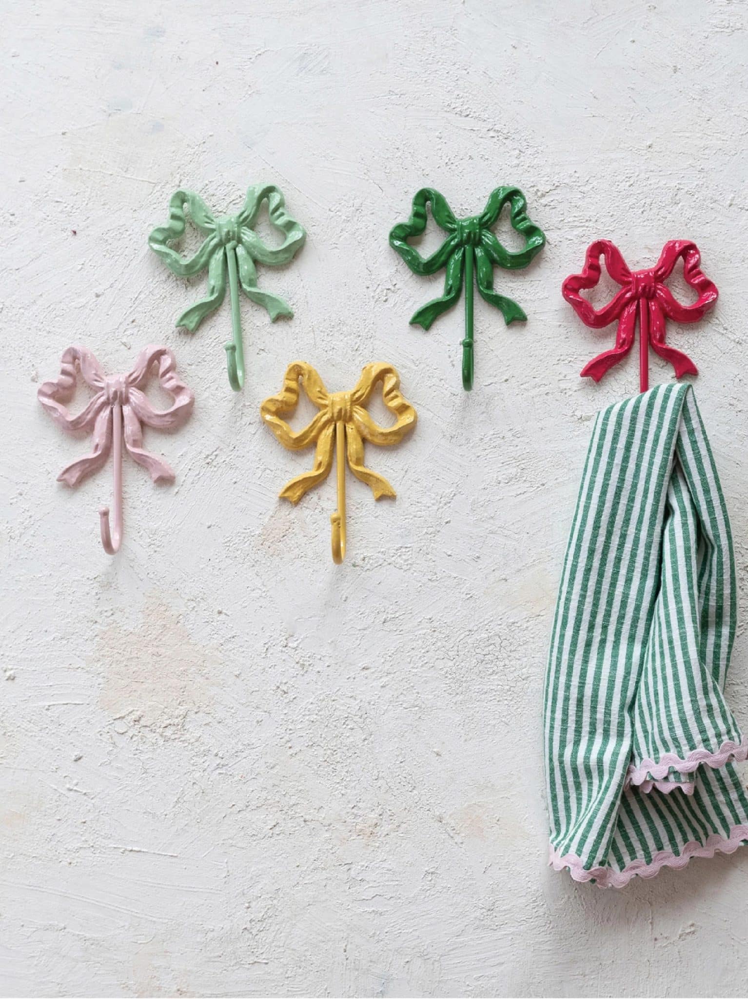 Cast Iron Bow Wall Hooks in assorted colors displayed on a textured wall.