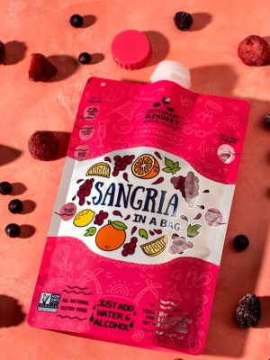 Sangria Cocktail in a Bag surrounded by frozen berries—easy wine cocktail mix made with real fruit, no blender needed.
