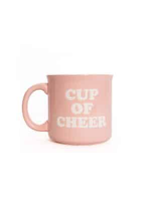 Light pink ceramic mug with white “Cup of Cheer” lettering, shown on a white background.