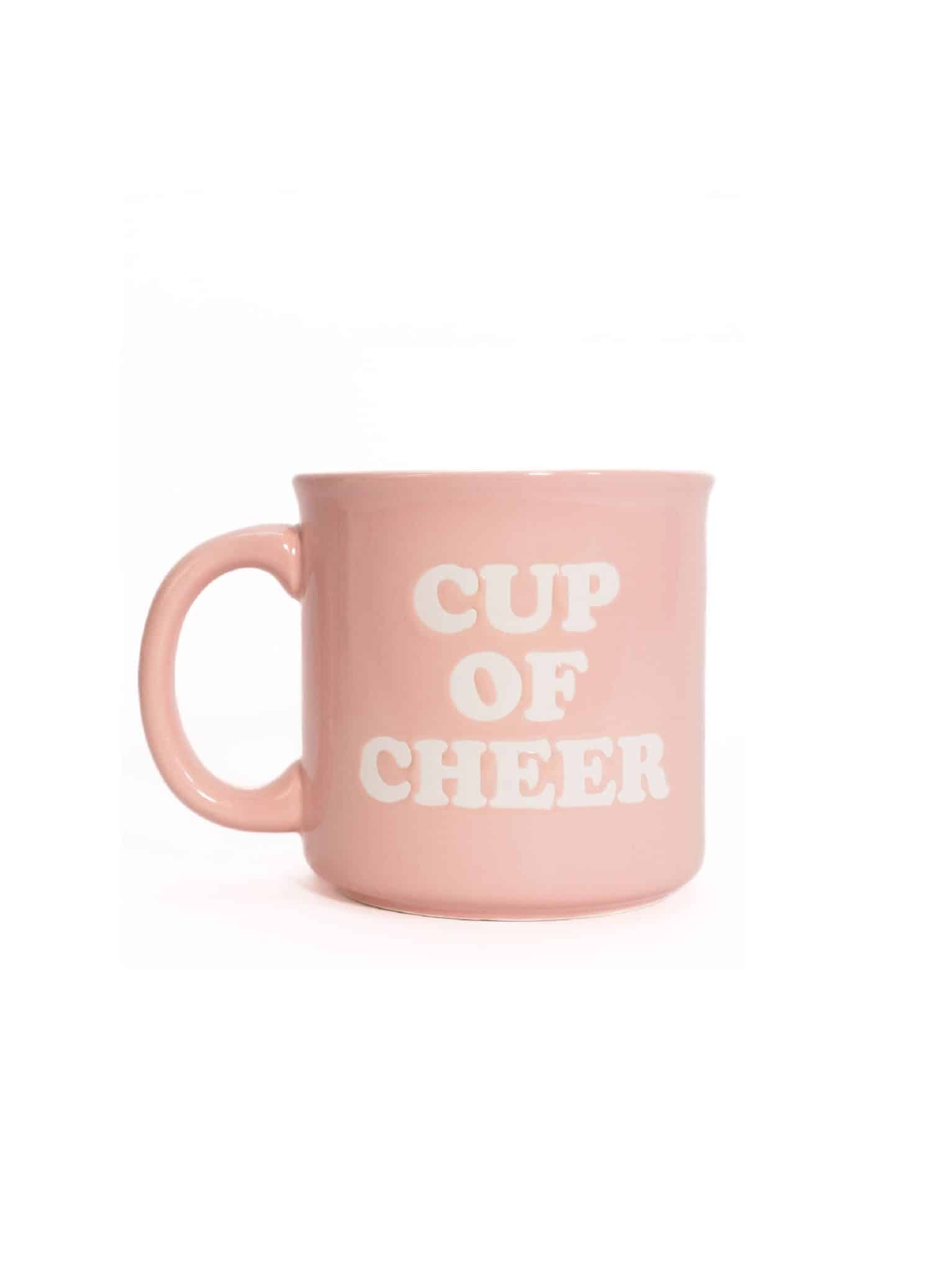 Light pink ceramic mug with white “Cup of Cheer” lettering, shown on a white background.