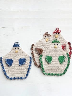 Four crocheted chicken-shaped potholders in assorted colors (blue, brown, green, and red) with scalloped trim and hanging loops, displayed on a white surface.
