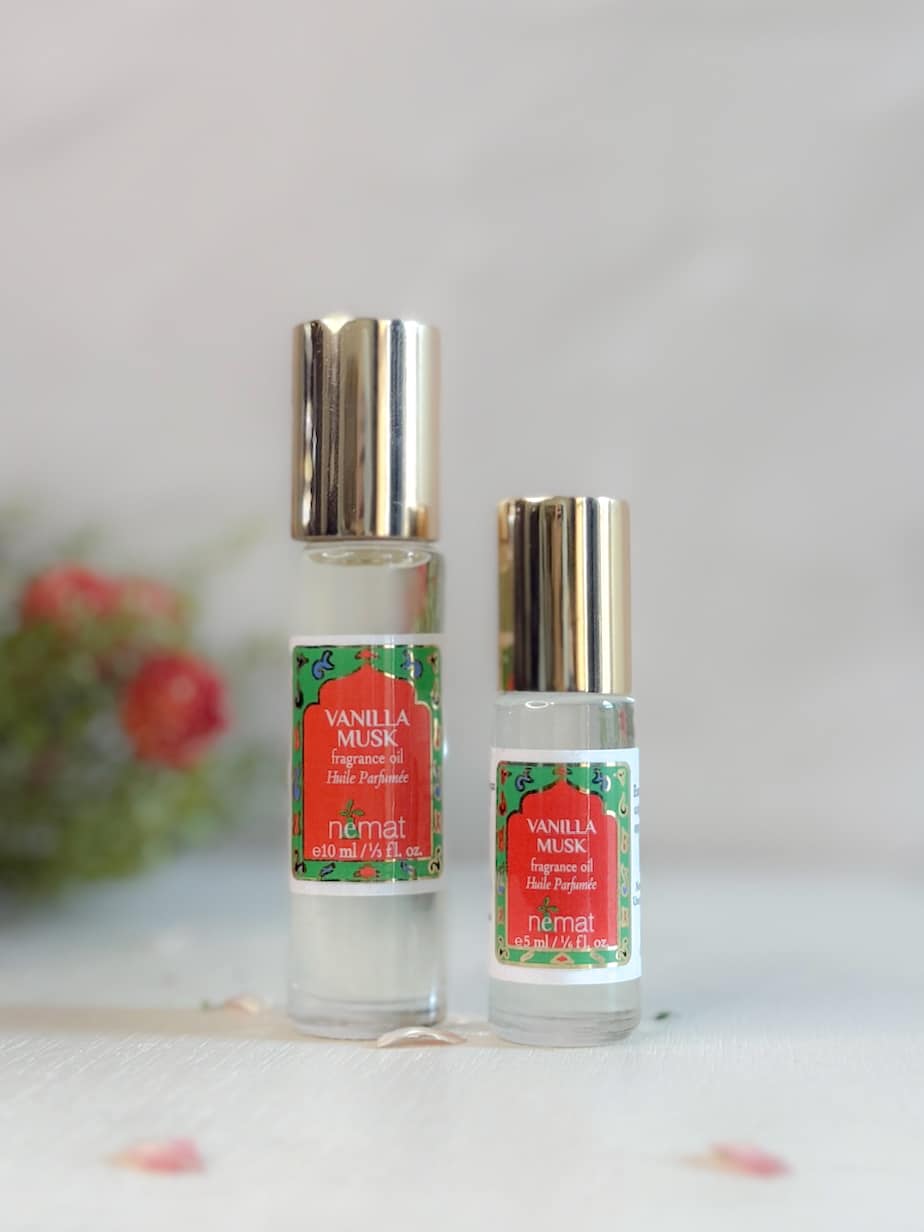 Two bottles of Vanilla Musk Perfume Oil by Nemat, one full-size and one mini, with metallic caps and red-and-green labels