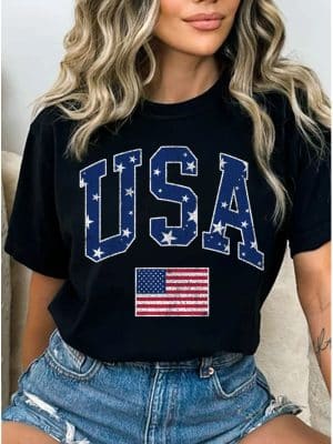 Alt Text: Black t-shirt with bold USA stars and flag graphic, paired with high-waisted denim shorts.