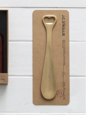 Brass-toned Shoe Horn and Bottle Opener with “Best Foot Forward” engraving, mounted on kraft card