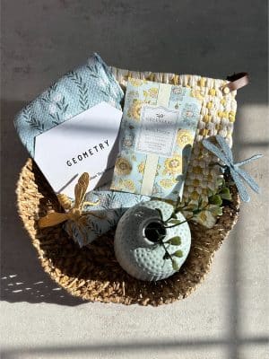 Gift basket with tea towel, scented sachet, potholder, vase, and pewter insect accents.
