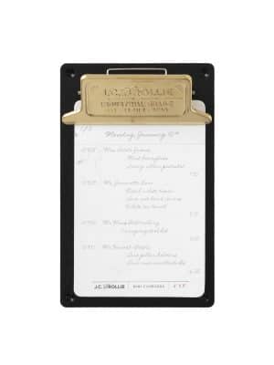 Mini black aluminum clipboard with a gold-toned brass clip holding a handwritten list