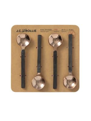 Flat lay of four copper mini spoons with black handles displayed on a kraft paper card backing.