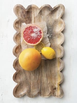 Overhead view of a scalloped wood tray styled with grapefruit and lemons.