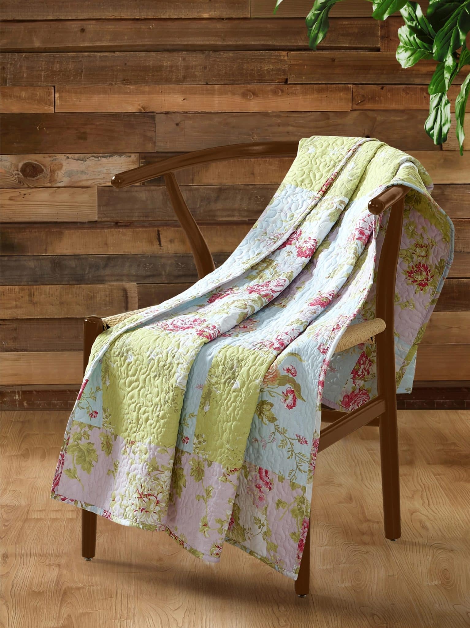 Cottage-style quilt throw blanket draped over wooden chair in rustic setting