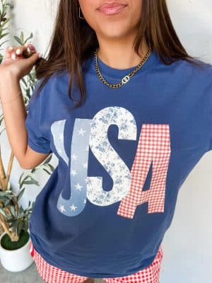 Woman wearing USA Patchwork Graphic Tee in China Blue with red gingham shorts, styled for 4th of July.