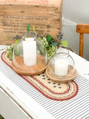 Wood & Glass Hurricane Candle Holders styled on layered patriotic table runners with greenery and candles.