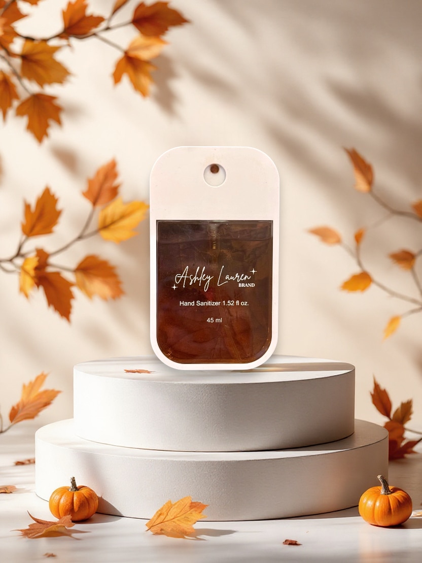 Caramel Hand Sanitizer Spray in slim white case with rich brown liquid, styled with pumpkins and fall leaves.